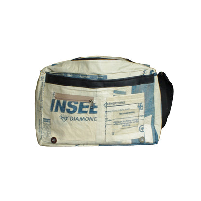Messenger bag made from repurposed Insee Diamonds cement sack, featuring blue and white printed panels, a black zipper pocket, and a black carrying handle, shown against a plain white background.